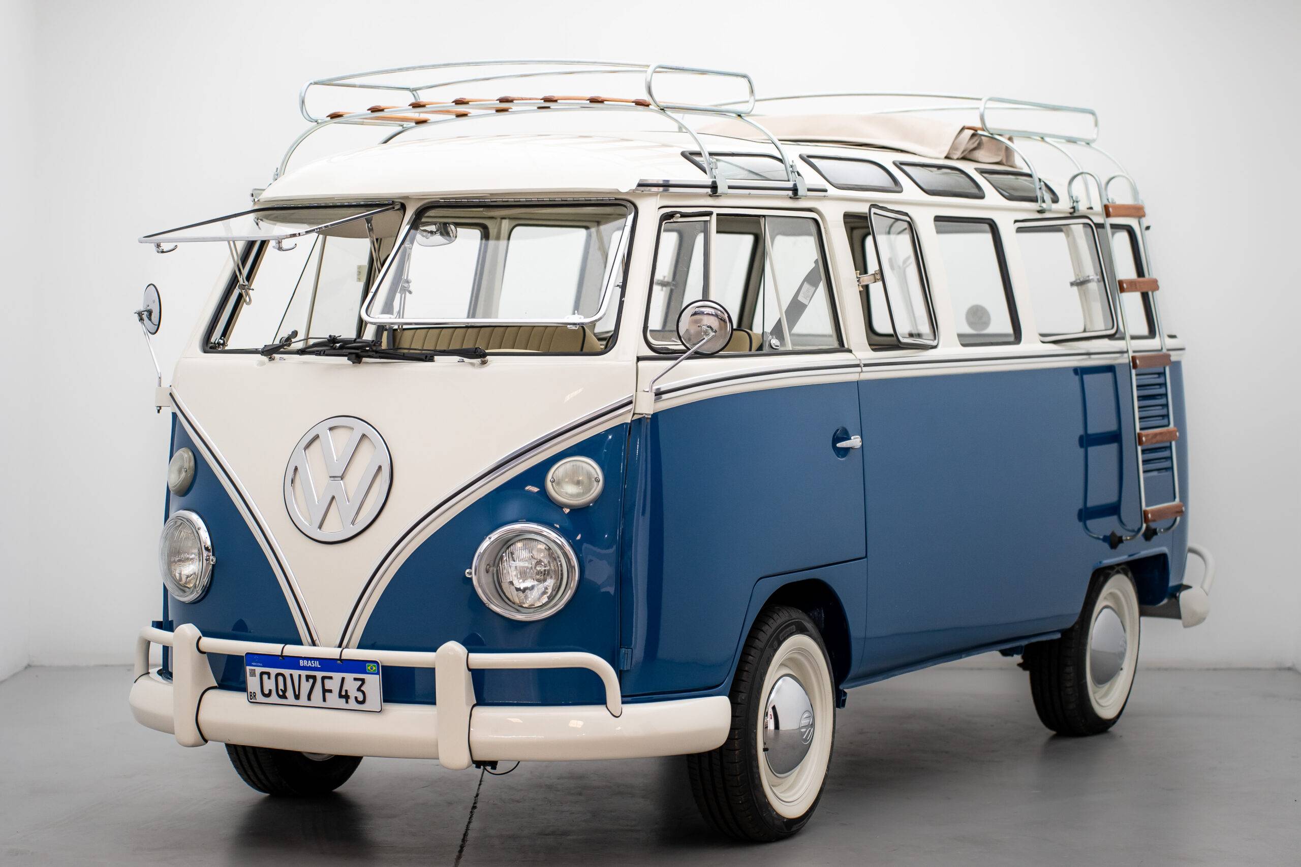Volkswagen T1 azul e branca com janelas panorâmicas, acabamento deluxe e para-brisa dividido.