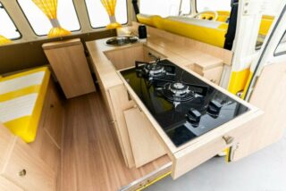 Custom-built kitchen module inside a restored Volkswagen T2 Camper, including a sink and 12V fridge.